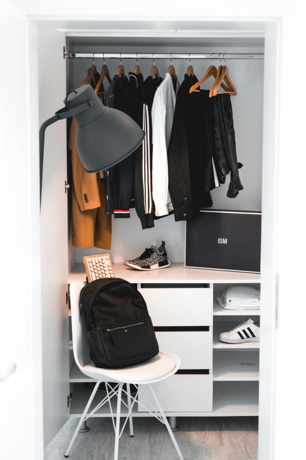 Black backpack on white chair beside cabinet photo